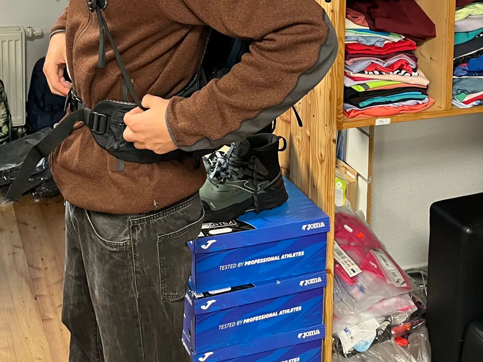 Der Hüftgurt eines Trekkingrucksacks wird beim Anprobieren geschlossen, dahinter die Rucksackwand im Outdoor- & Sporttreff Neustadt