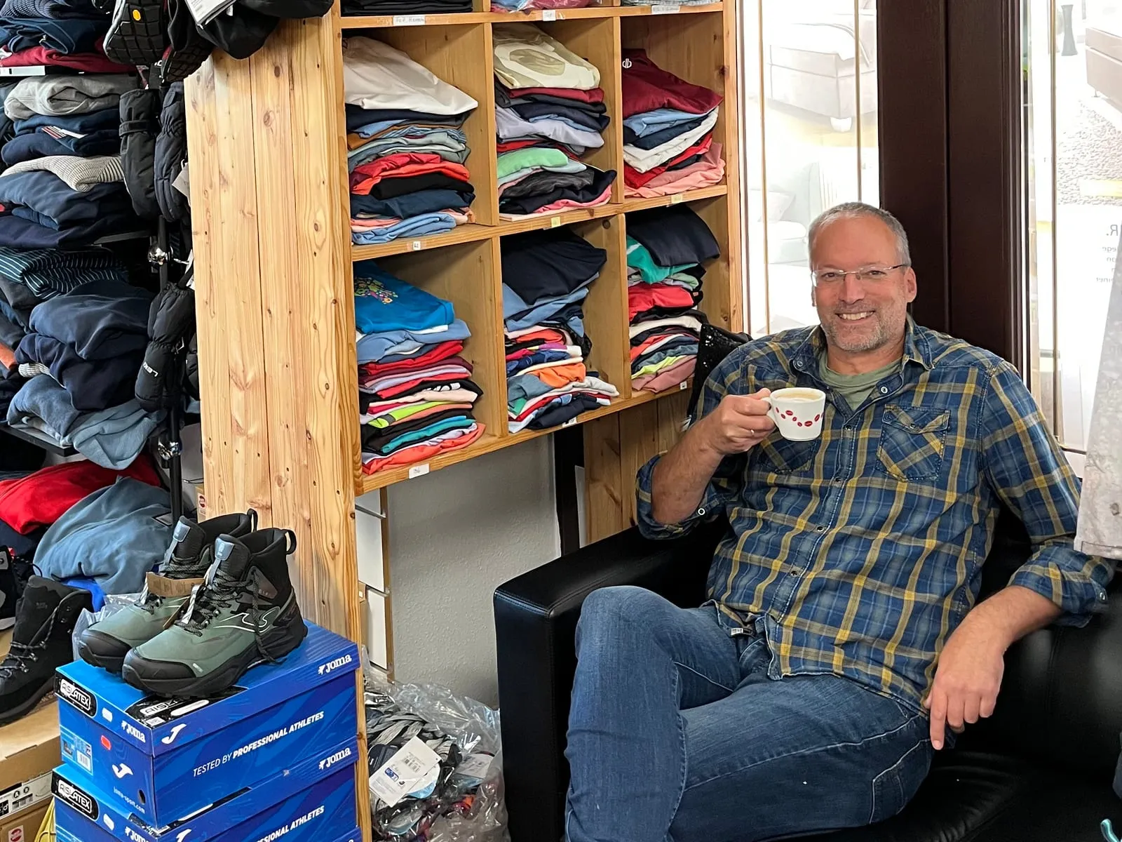 Matthias Arlt mit einer Tasse Kaffee auf dem Sofa im Outdoor- & Sporttreff Neustadt